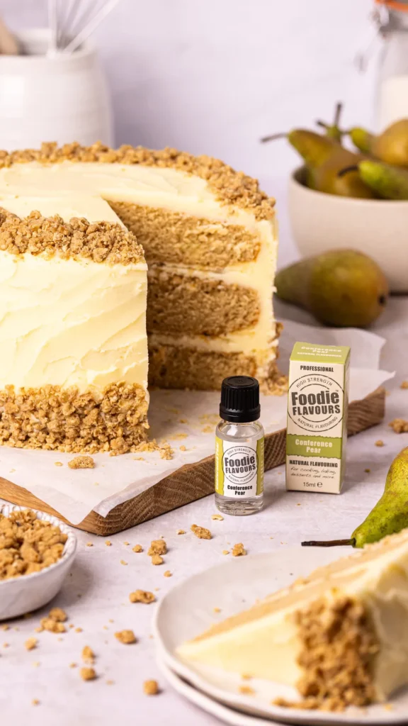 Glass bottle of foodie flavours conference pear natural food flavouring, next to conference pear flavoured pear crumble cake